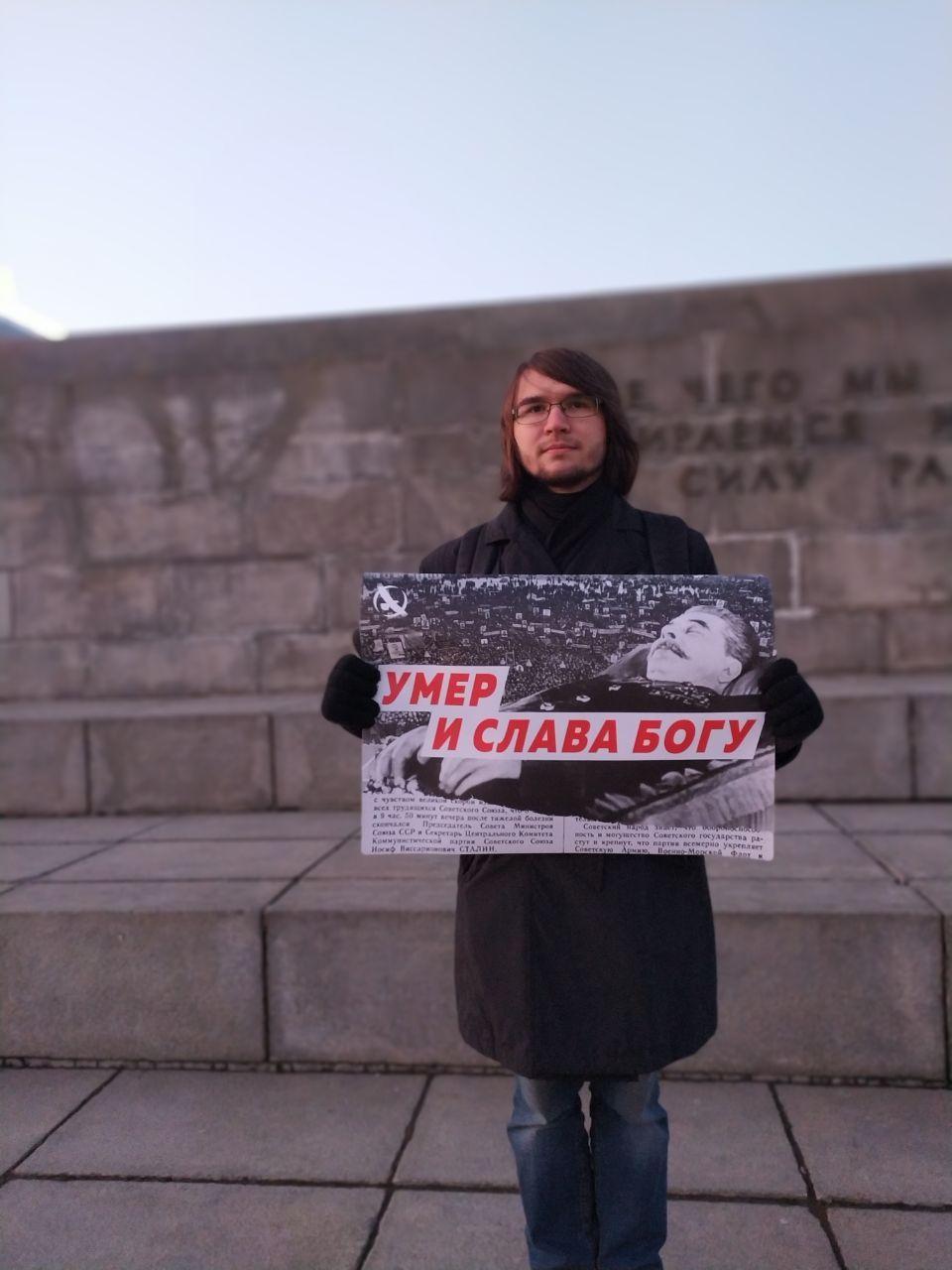 Активист с плакатом "Умер и слава богу" у памятника Ленину